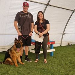 A man and woman standing next to a dog.