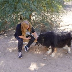 A woman kneeling down next to a dog.