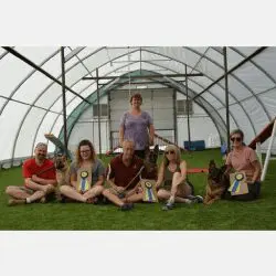 A group of people sitting in the grass under a large structure.