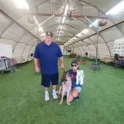 A man and woman with two dogs in an indoor tent.