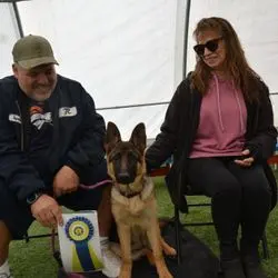 A man and woman sitting next to a dog.