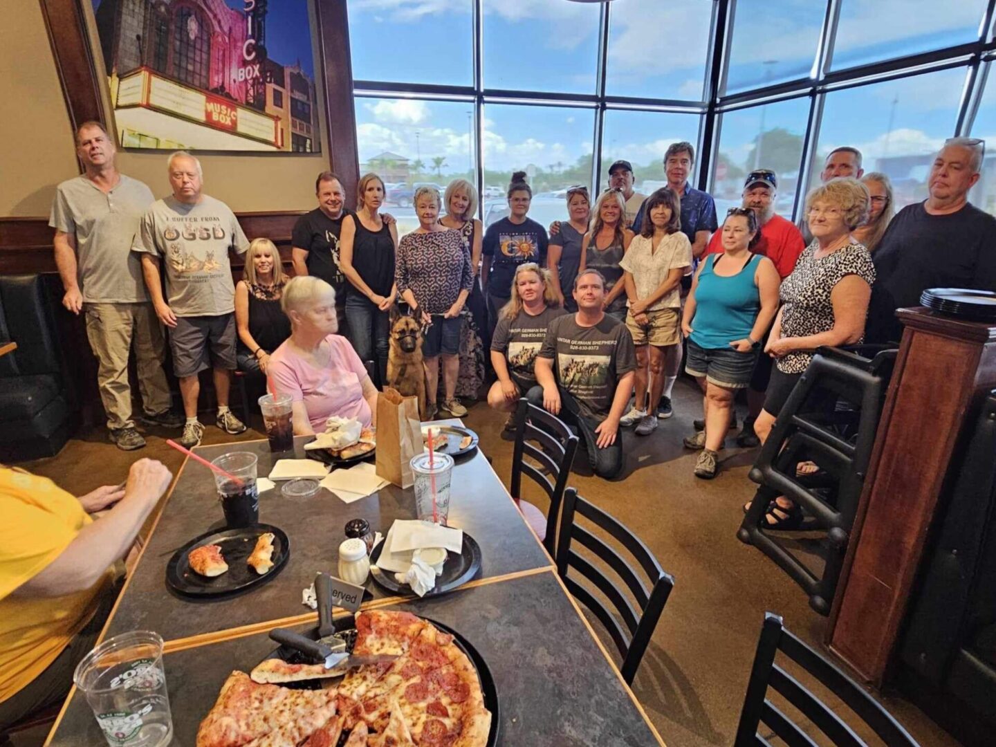 A group of people standing around a table with pizza.