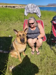 A woman sitting in an outdoor chair with her dog.