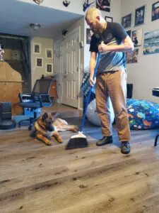 A man and his dog are cleaning the floor.