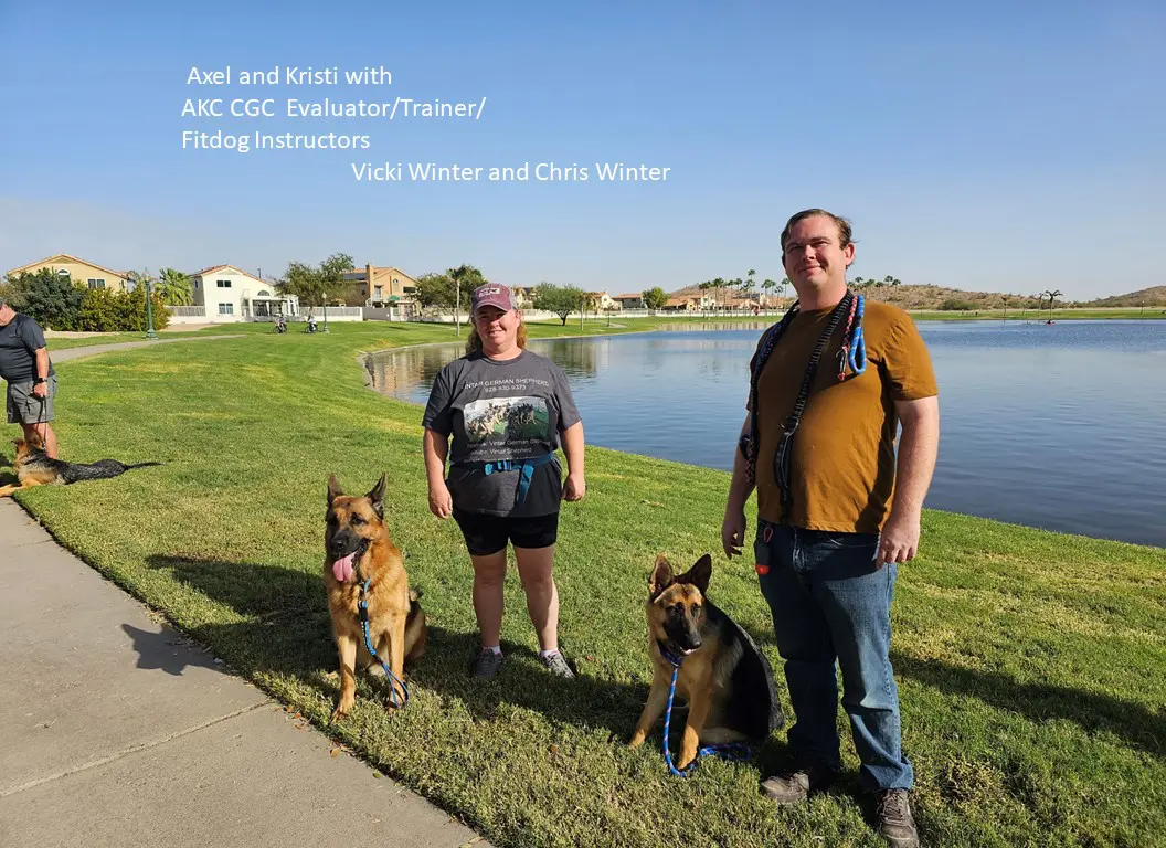 A man and woman with two dogs in front of water.